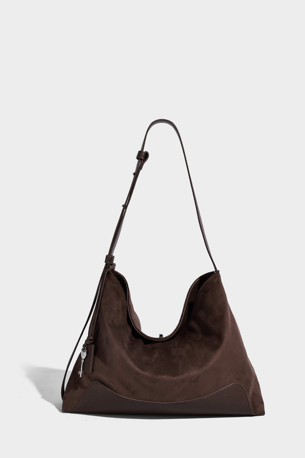 Dark brown slouchy hobo bag with matte suede-look body, smooth leather-look base trim, adjustable shoulder strap, and, detail