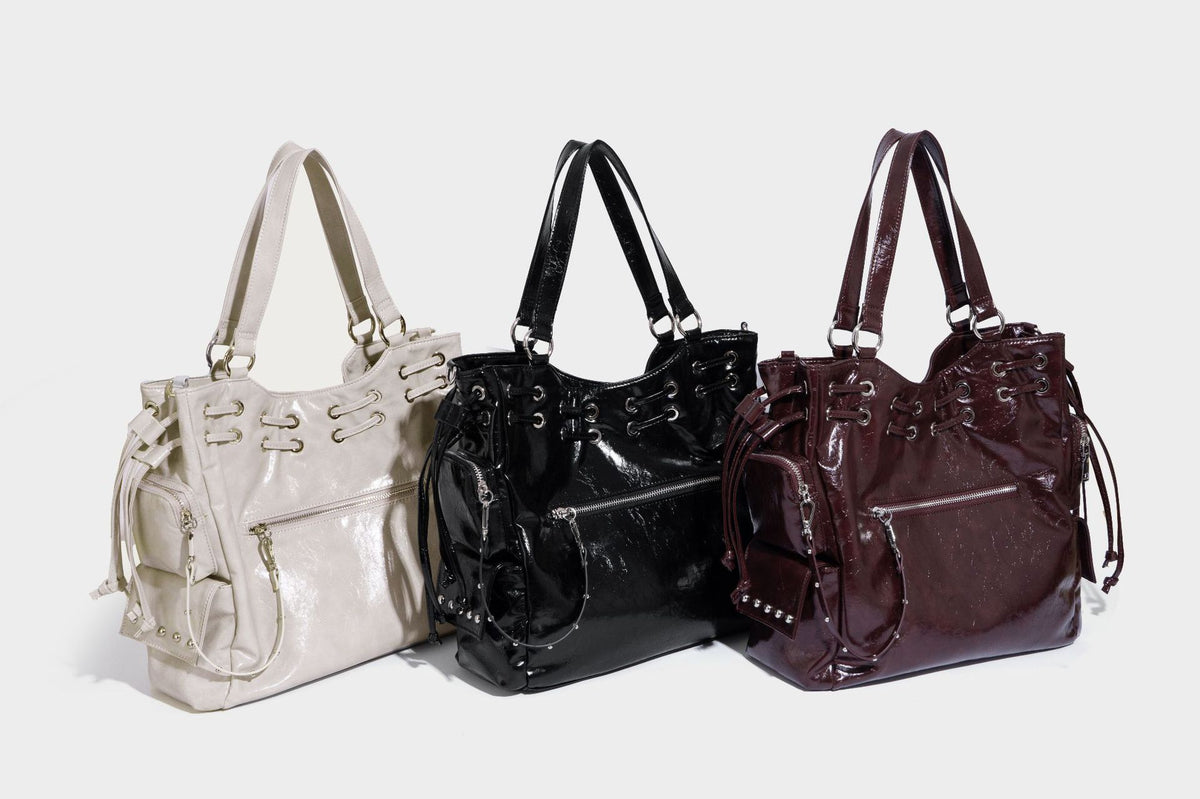Glossy crinkled leather-look tote bag with silver grommet lace-up front detail, dual top handles, and detachable shoulder