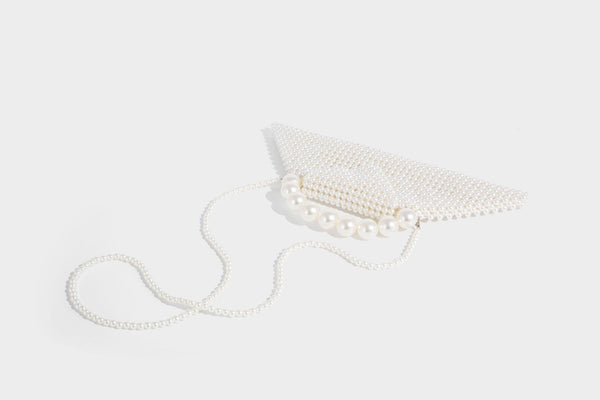 Small structured triangle clutch bag covered in glossy pearl beads with an arched pearl top handle and silver snap closure