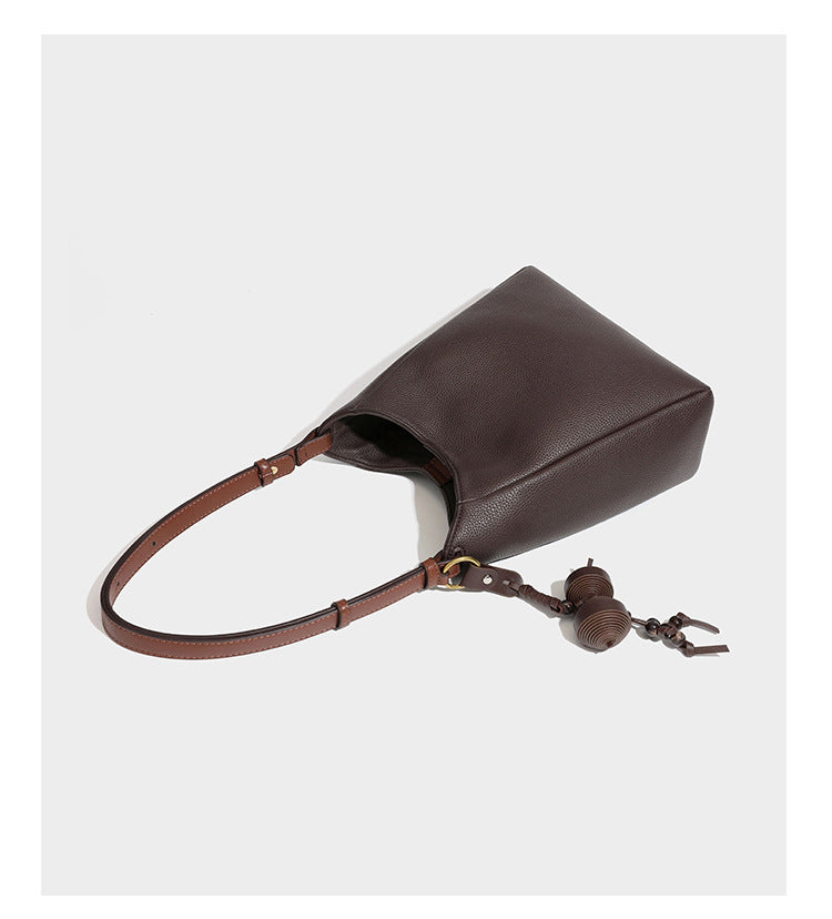 Hobo-Schultertasche in dunklem Espresso mit genarbter Oberfläche, warmen cognacfarbenen Details, verstellbarem schmalem Riemen, goldfarbenen Ringbeschlägen und geknotetem