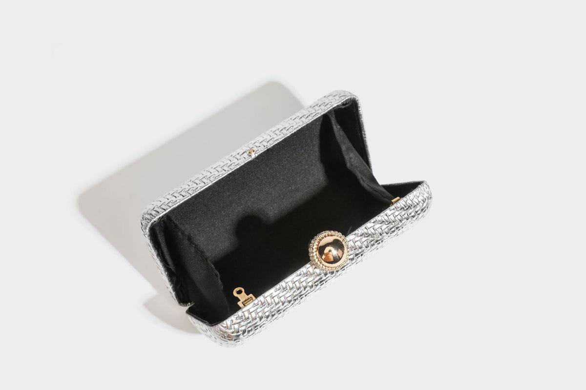Small structured metallic woven-texture box clutch bag with jeweled kiss-lock dome clasp and slim gold chain strap, detail