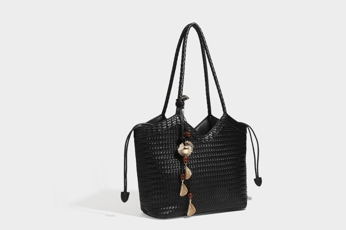 Olivgrüne Tote-Bag in Korbgeflecht-Optik mit dunkelbraunen geflochtenen Schulterriemen, seitlichen Kordelzügen und Perlenanhänger in Goldoptik
