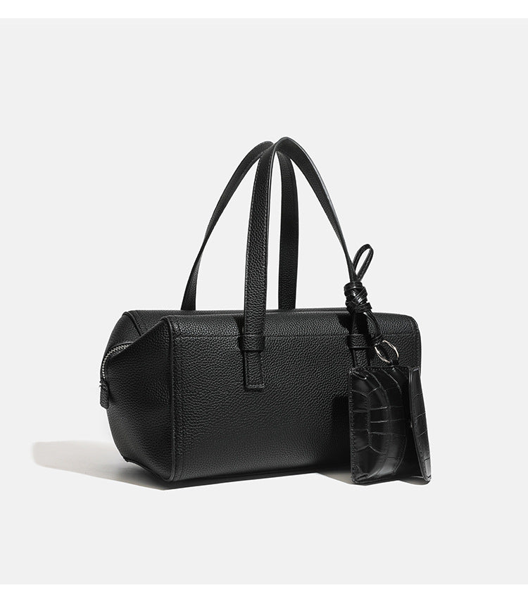 Structured pebbled leather-look top-zip barrel bag with dual handles, detachable shoulder strap, and attached croc-pattern