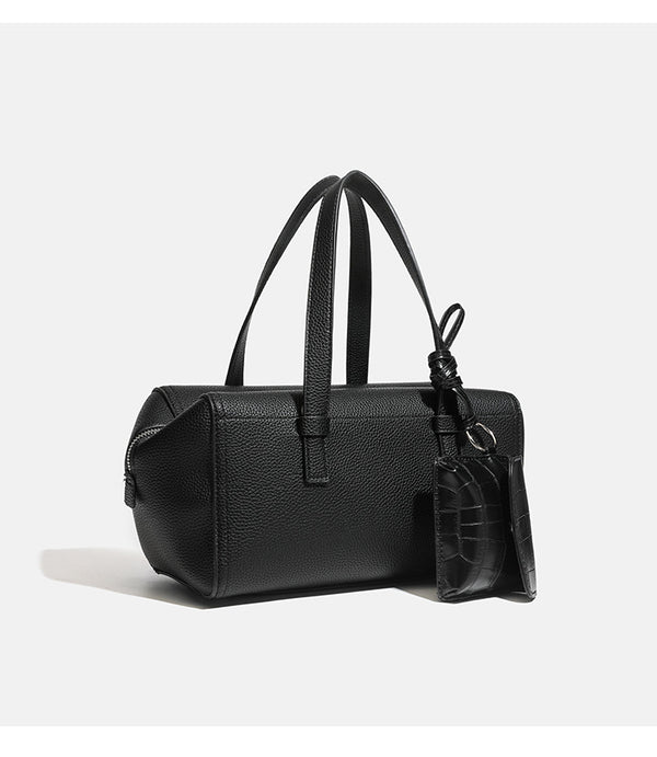 Structured pebbled leather-look top-zip barrel bag with dual handles, detachable shoulder strap, and attached croc-pattern