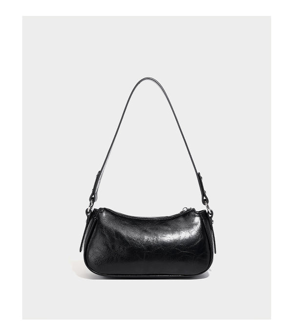 Compact moto-inspired shoulder bag with crisscross grommet strap detail, glossy textured finish, and adjustable crossbody