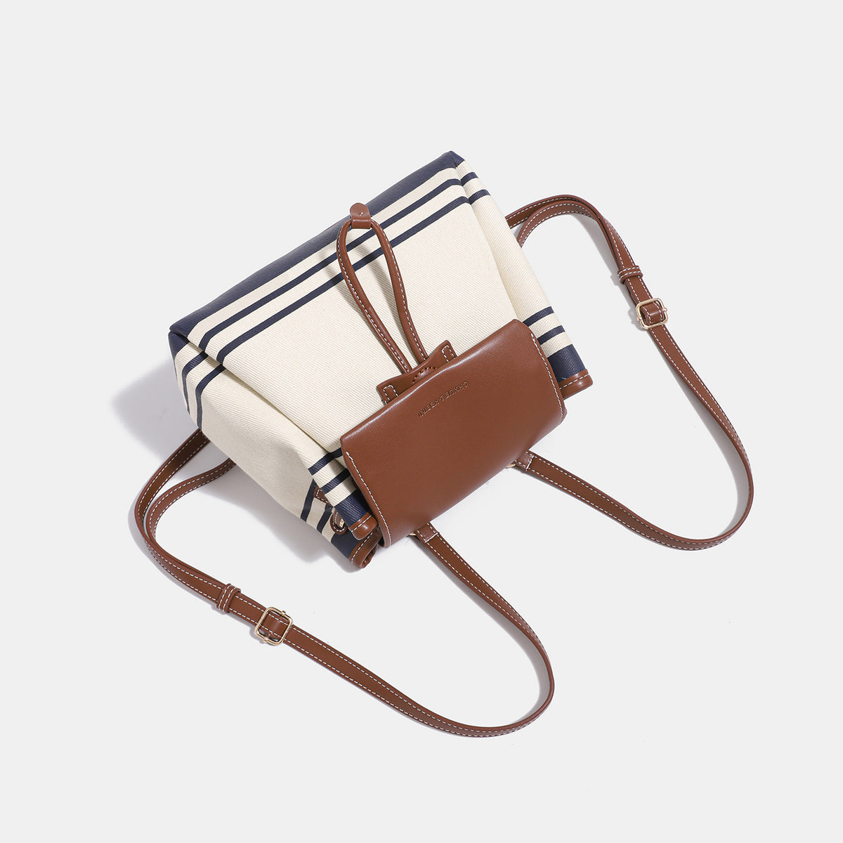Cremefarbene Canvas-Beuteltasche mit marineblauen horizontalen Streifen, cognacfarbenem Kunstleder-Lappen und -Besatz, goldfarbenen Metalldetails und wandelbarer Trageweise