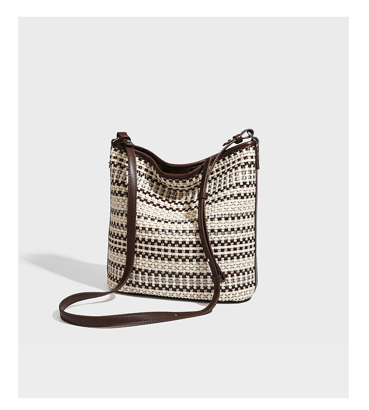 Woven stripe bucket shoulder bag in cream and dark brown with leather-look trim, knotted adjustable strap, and small shield