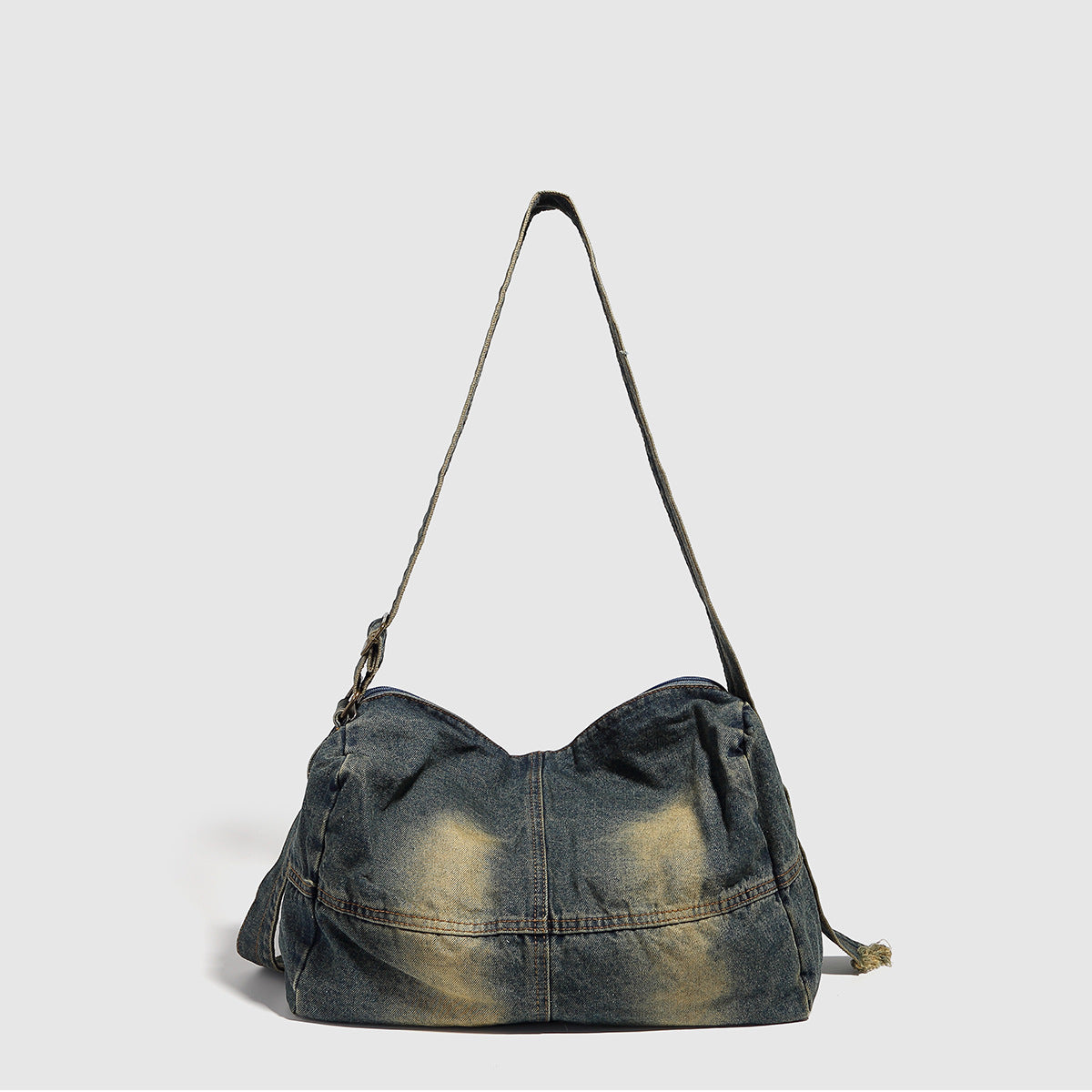 Slouchy washed denim shoulder bag with faded distressed finish, zip-top closure, and antique brass-tone adjustable strap