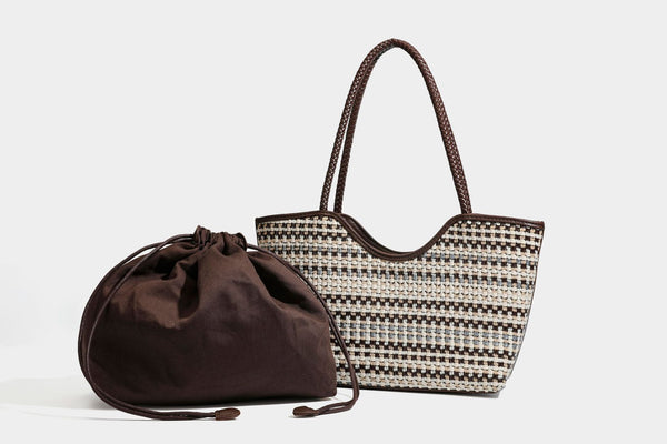 Large woven checker-pattern tote bag with dark braided shoulder straps, leather-look trim, and drawstring side ties, detail