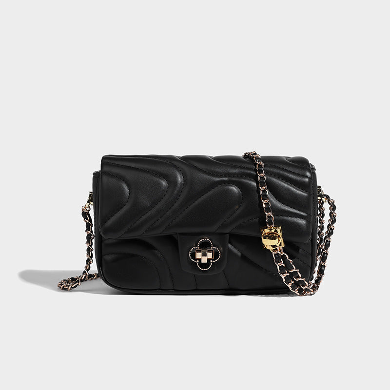 Compact cream quilted flap crossbody bag with wave stitching, gold-tone chain strap, and four-petal turn-lock clasp, detail