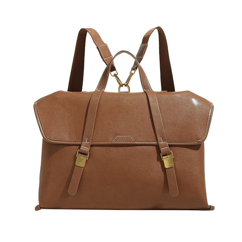 Structured flap-over backpack satchel in smooth leather-look finish with gold-tone buckle hardware and top handle, detail