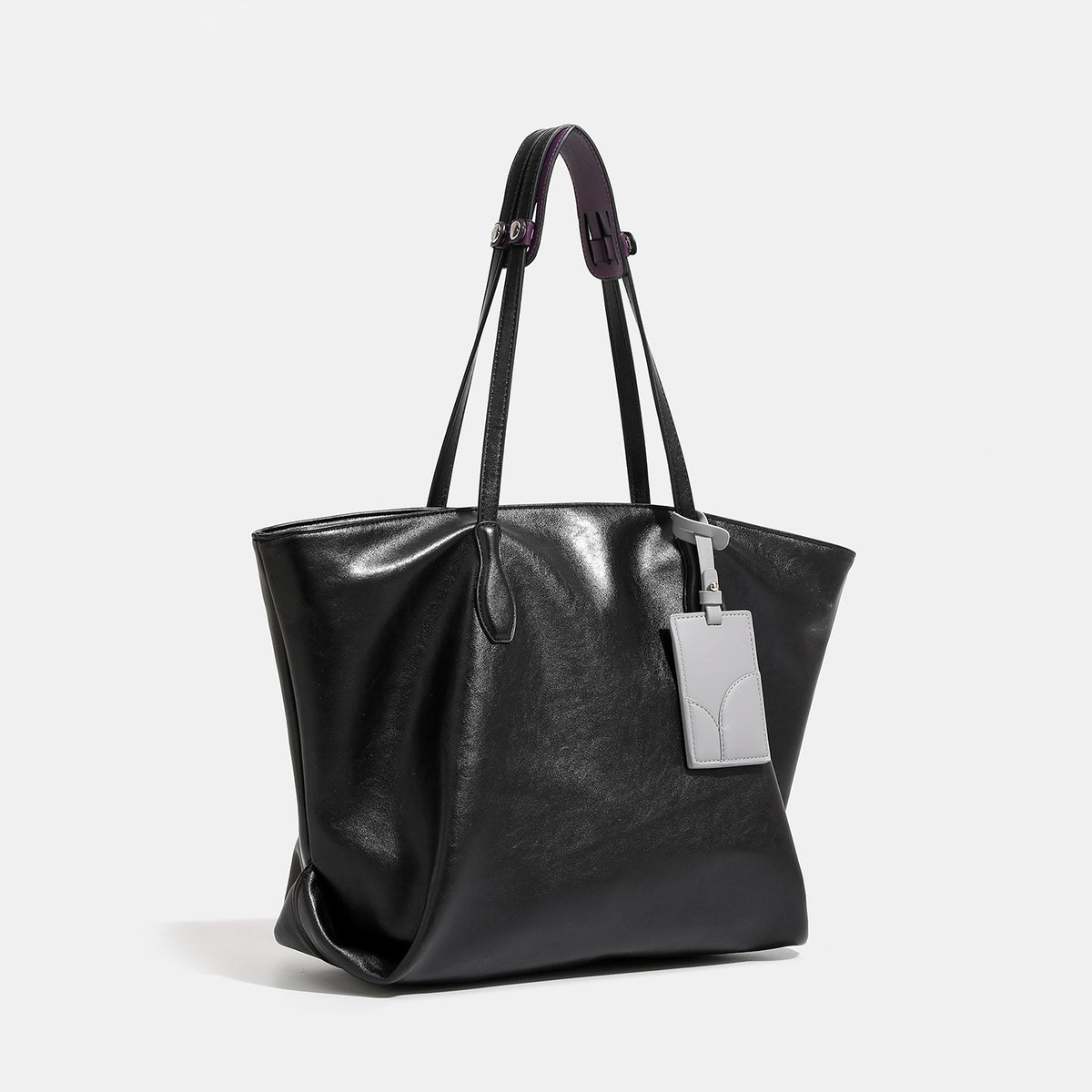 Large soft trapezoid tote bag with leather-look finish, dual shoulder straps, and gray hanging card tag, detail view 3