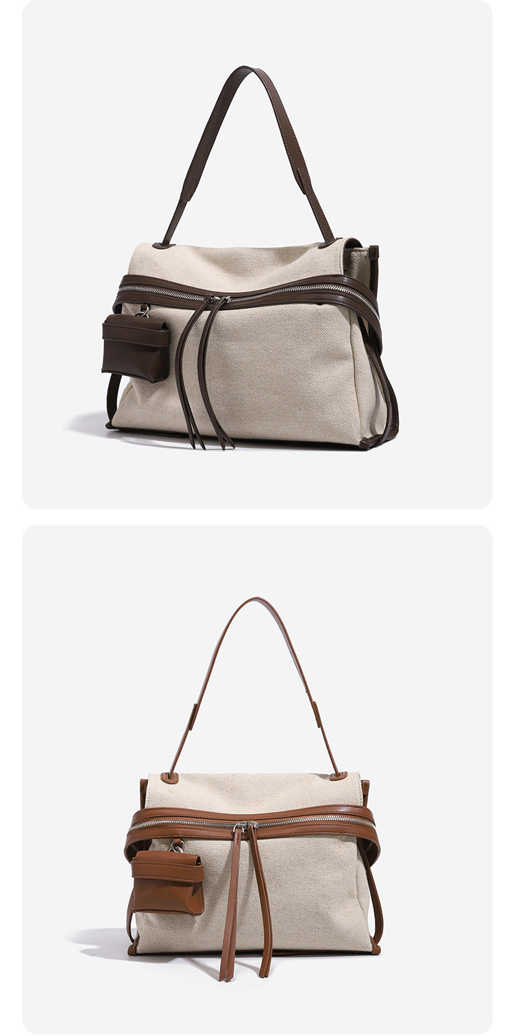 Cream canvas messenger shoulder bag with tan leather-look trim, dual zippers, tassel pulls, and attached mini front pouch