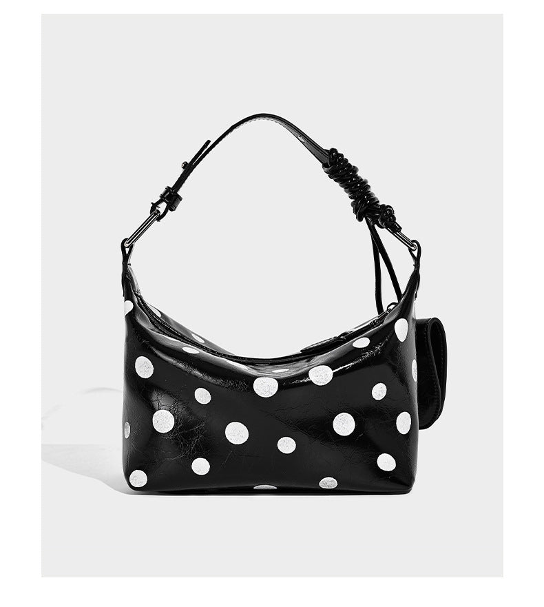 Schultertasche in glänzender Lederoptik mit Punktemuster, aufgesetztem Mini-Fronttäschchen, Reißverschluss oben und verstellbarem Riemen, Detailansicht