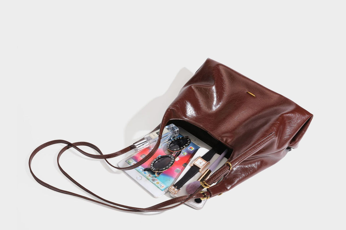 Locker fallende Hobo-Schultertasche mit offenem Oberteil aus glänzendem, geknautschtem Lederimitat in Dunkelbraun, mit schmalem verstellbarem Riemen und goldfarbenem