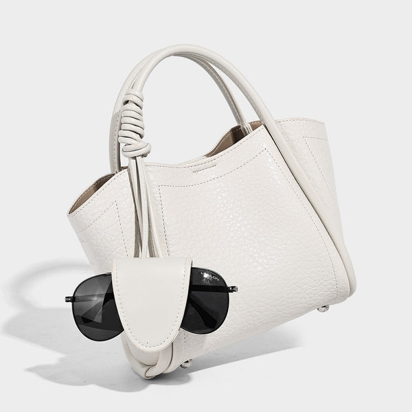 Structured mini tote bag in pebbled leather-look finish with knotted top handles, front flap pocket, and detachable shoulder