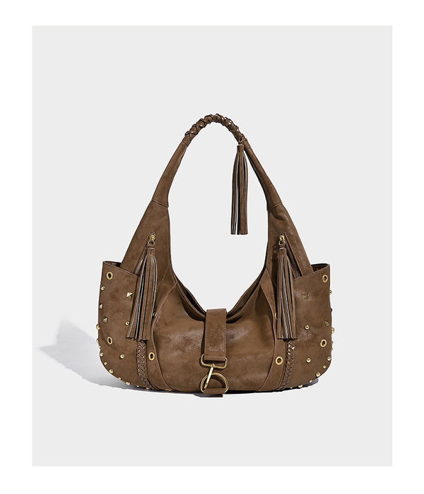 Slouchy crescent hobo bag in matte brown suede-like finish with gold-tone studs, grommets, braided top handle, tassel side