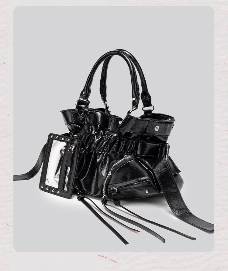 Black glossy ruched convertible tote bag with silver-tone rivets, detachable wide shoulder strap, external zip pouch, and