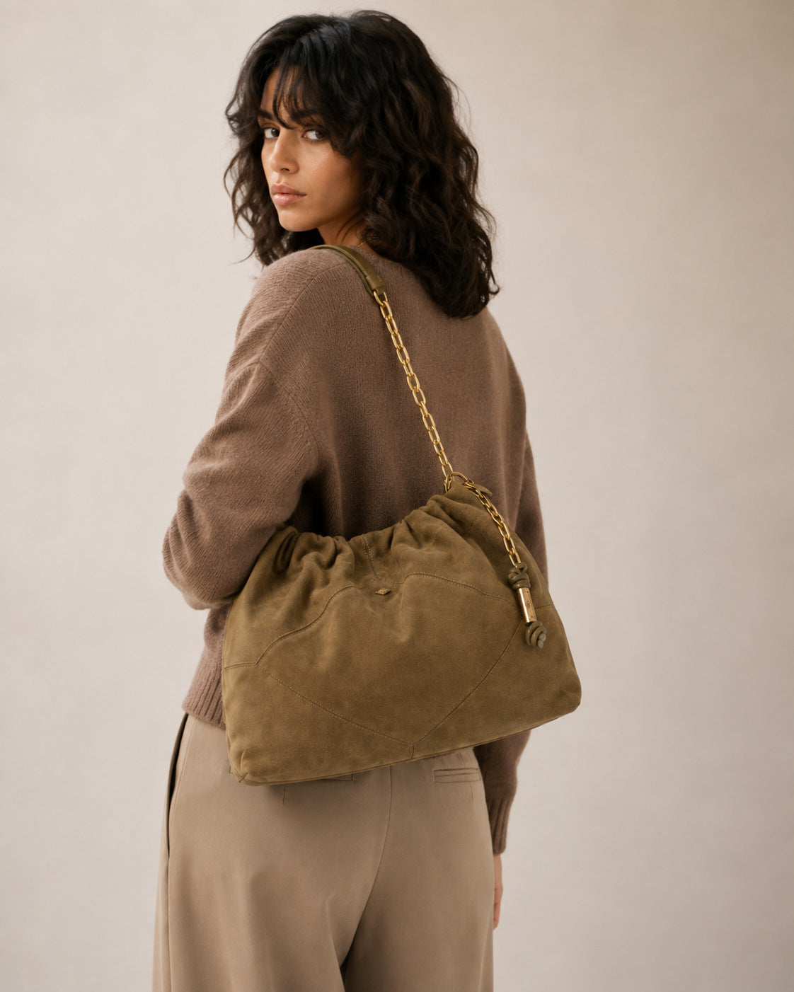 Slouchy suede-look shoulder bag with gathered top, angular stitched paneling, and chunky gold-tone chain strap, detail view