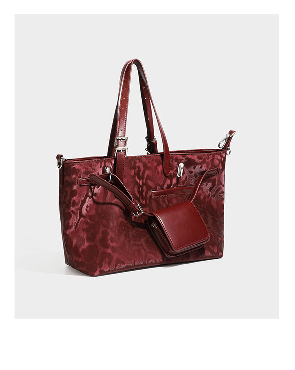 Glossy leopard-print tote bag with leather-look dark trim, dual top handles, detachable shoulder strap, and attached front