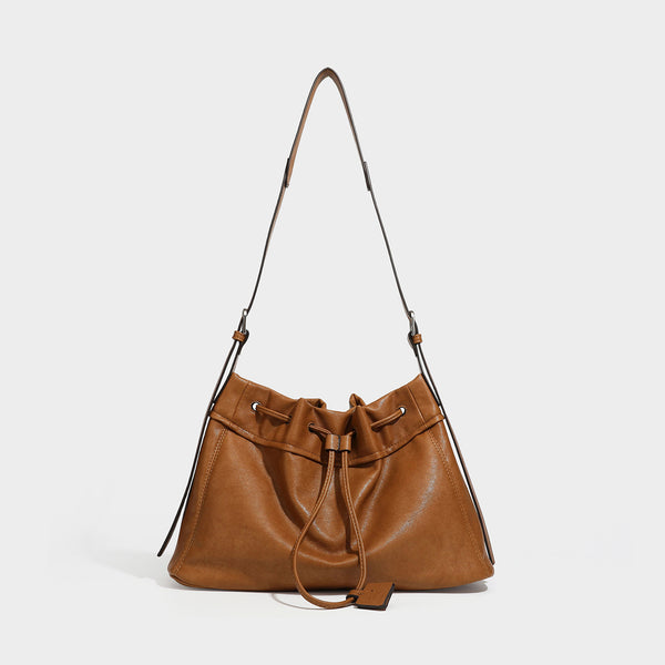 Slouchy drawstring bucket bag in dark brown leather-look finish with long adjustable shoulder strap and gathered tie closure