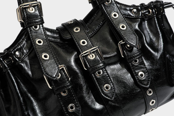 Large black glossy leather-look tote bag with silver buckle straps, eyelet grommet panels, drawstring side gathers, and