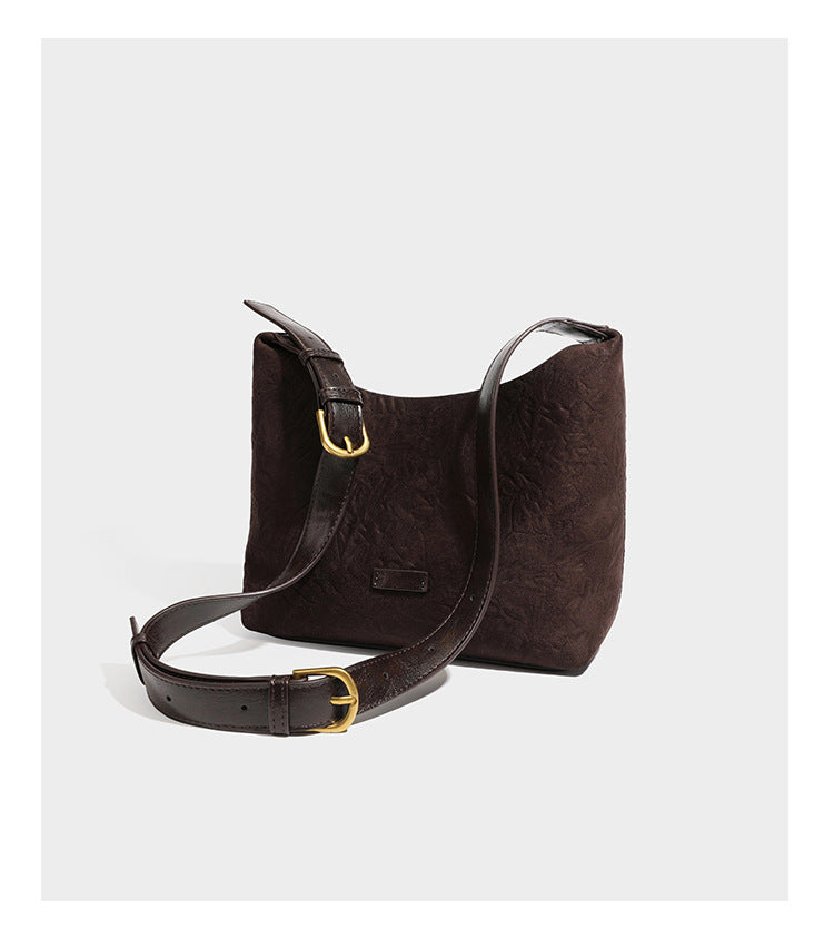 Dunkelbraune, lässig fallende Hobo-Schultertasche mit velourslederähnlich strukturierter Oberfläche, glatter lederähnlicher Paspelierung und Details in Antikgoldoptik, Detailansicht