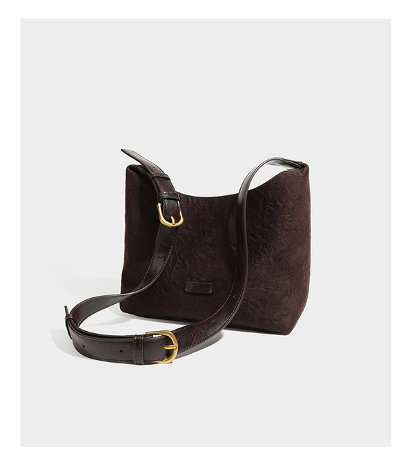 Dunkelbraune, lässig fallende Hobo-Schultertasche mit velourslederähnlich strukturierter Oberfläche, glatter lederähnlicher Paspelierung und Details in Antikgoldoptik, Detailansicht