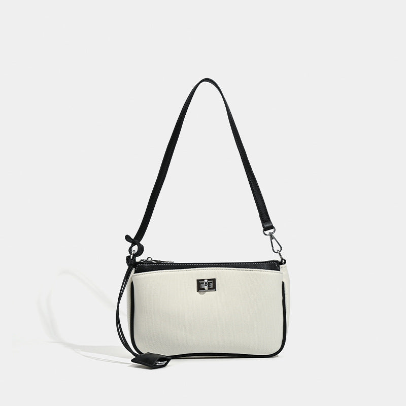 Small structured cream crossbody bag with contrast leather-look trim, silver-tone turn-lock hardware, and adjustable