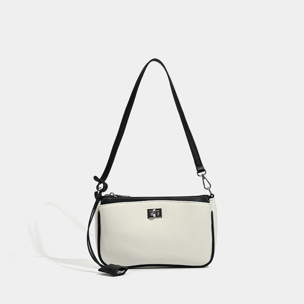 Small structured cream crossbody bag with contrast leather-look trim, silver-tone turn-lock hardware, and adjustable