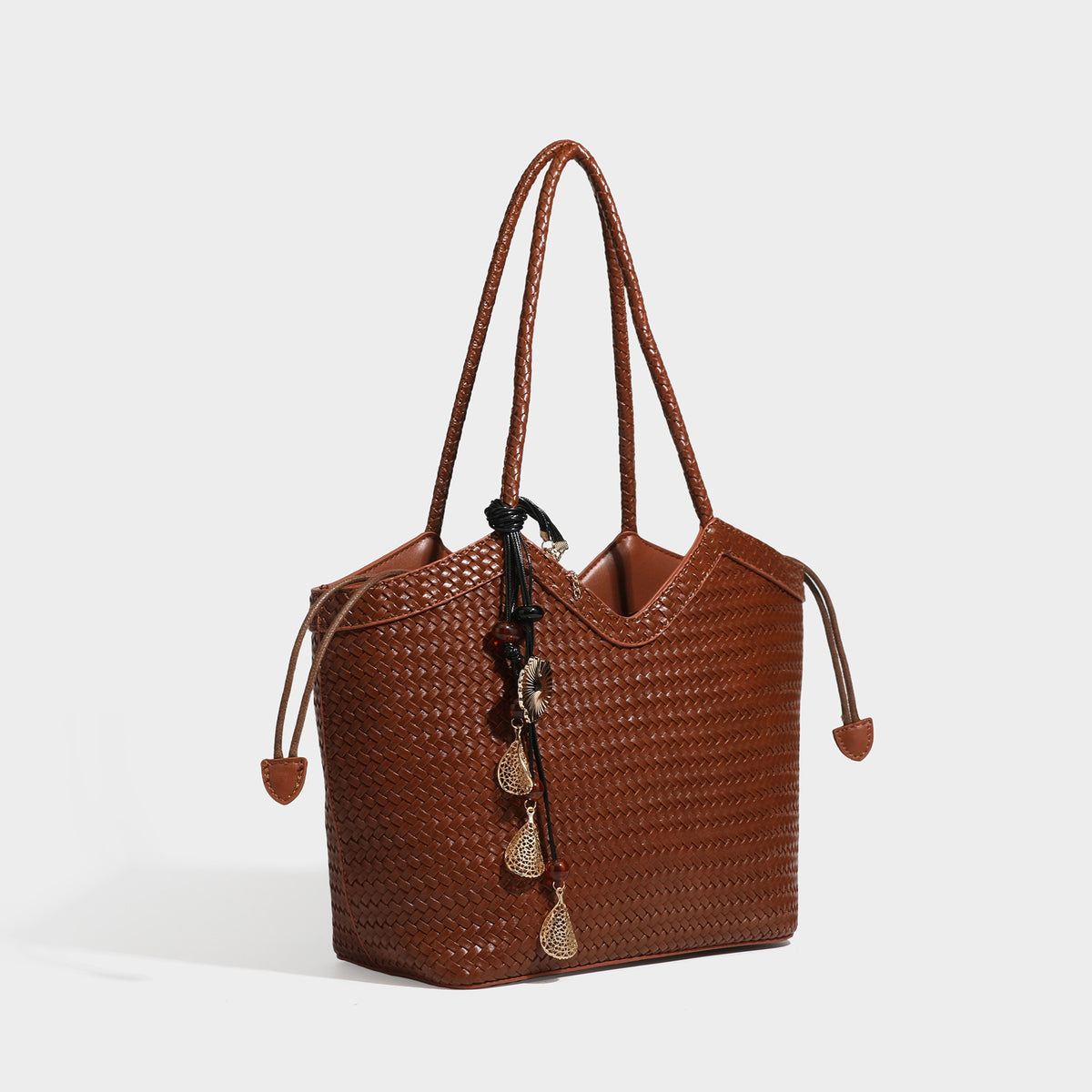 Olivgrüne Tote-Bag in Korbgeflecht-Optik mit dunkelbraunen geflochtenen Schulterriemen, seitlichen Zugbändern und Perlenanhänger in Goldoptik
