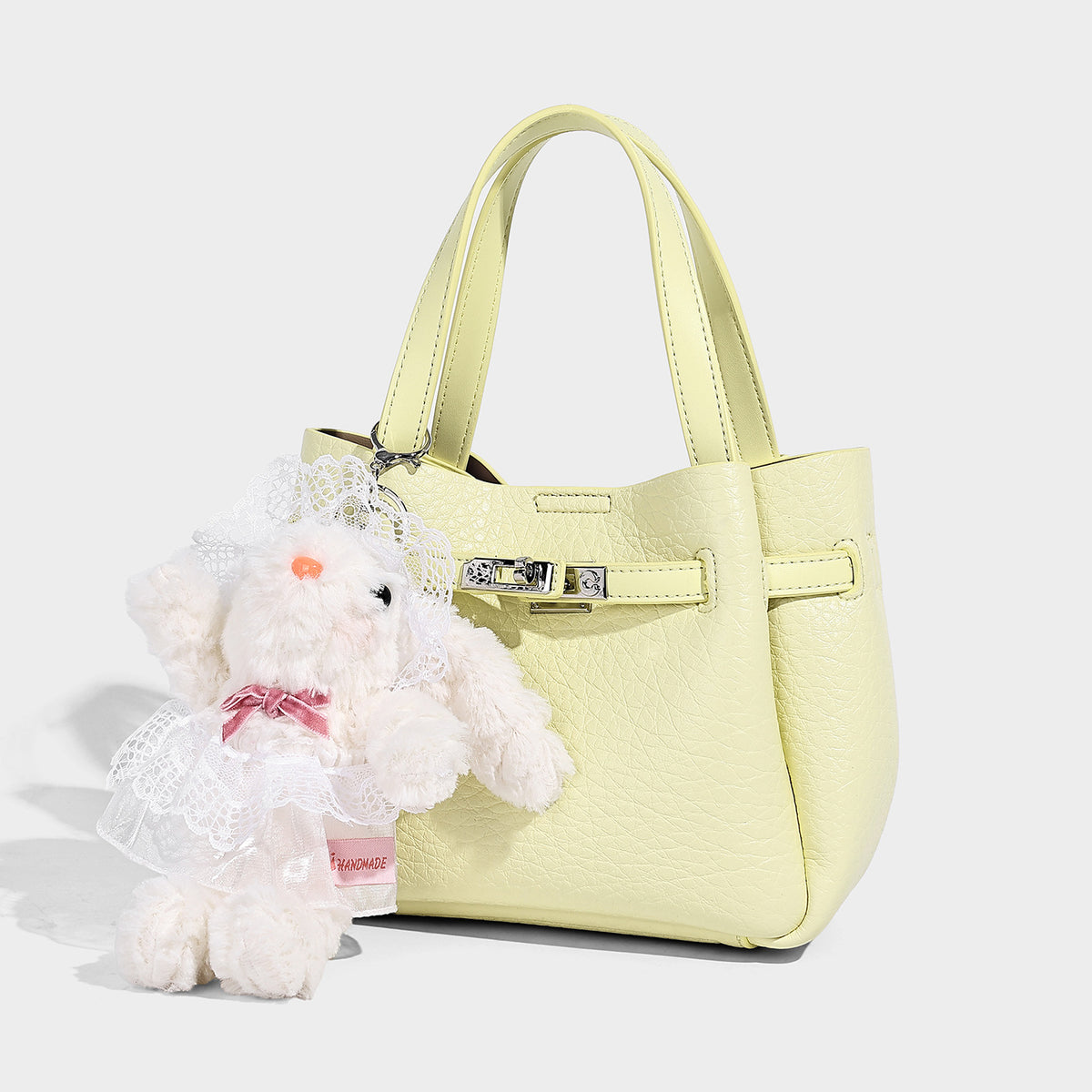 Small structured pebbled bucket tote with double top handles, silver turn-lock hardware, and detachable shoulder strap