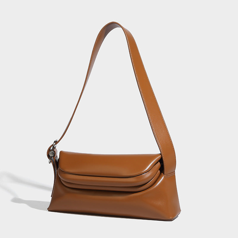 Compact structured baguette shoulder bag with smooth leather-look finish, zip top, and adjustable silver-buckle strap, detail