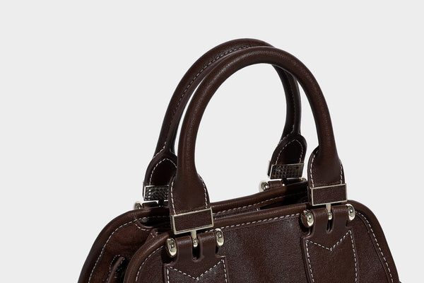 Kleine strukturierte Henkeltasche mit abgerundeten Tragegriffen, kontrastierenden weißen Steppnähten, Riegelverschluss in Silberoptik und abnehmbarem