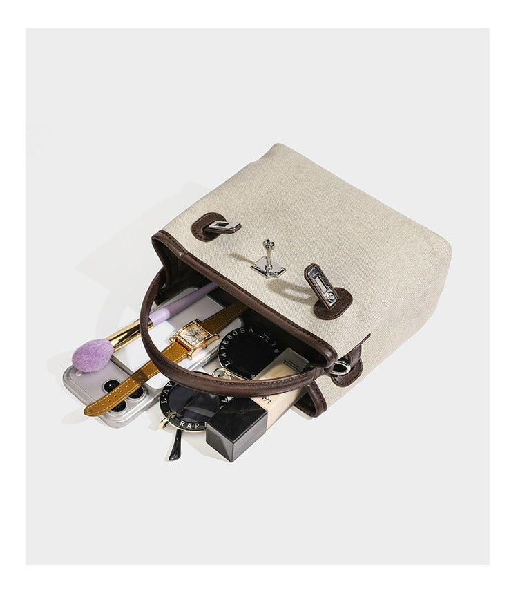Small structured beige canvas top-handle bag with dark brown leather-look trim, silver turn-lock hardware, and detachable