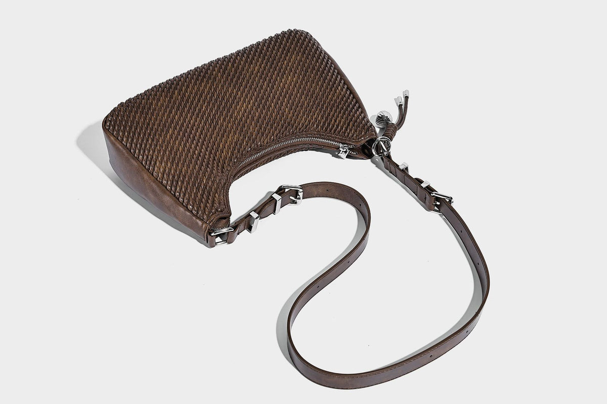 Woven crescent hobo shoulder bag with smooth side panels, zip-top closure, silver-tone charm hardware, and adjustable, detail