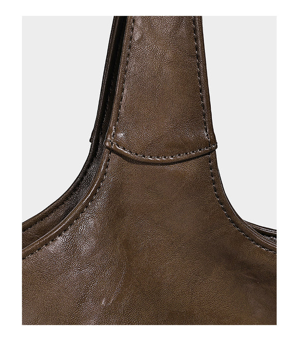 Large open-top tote bag with crinkled leather-look finish, long double shoulder straps, and embossed circular detail on