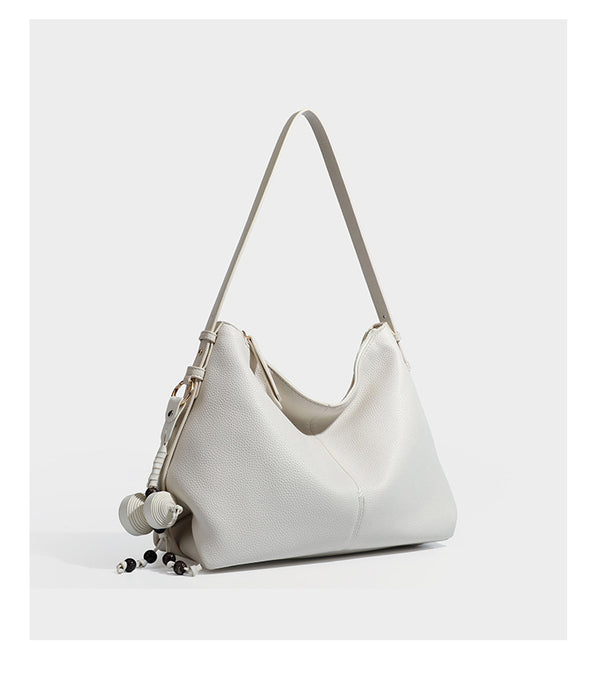 Slouchy hobo shoulder bag with pebbled leather-look finish, zip-top closure, gold-tone hardware, and hanging bead charm