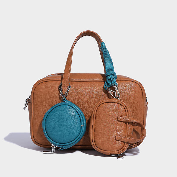 Structured pebbled leather-look Boston bowling bag in tan with blue detachable round mini pouch, dual top handles, and