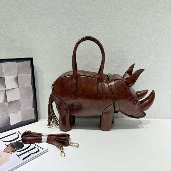 Rhinoceros-shaped 3D structured handbag with sculpted horns, four legs, tassel tail, twin top handles, and detachable, detail
