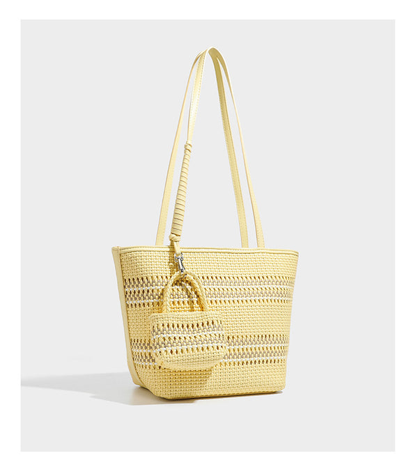 Large structured woven tote bag with striped basket-weave finish, long shoulder straps, and detachable mini pouch charm