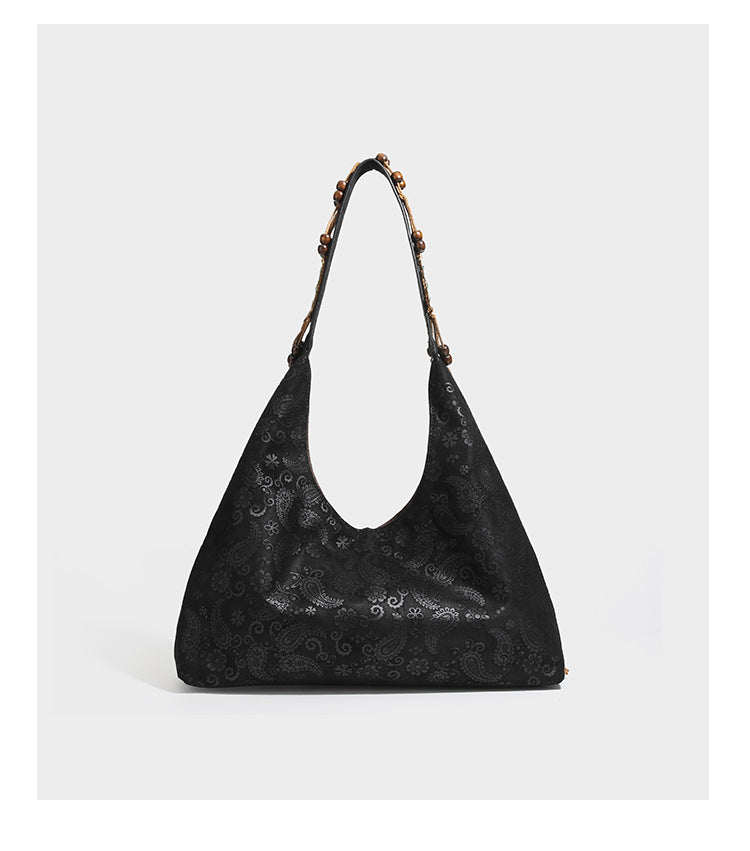 Slouchy boho hobo shoulder bag in embossed brown suede-look finish with beaded strap, cord tassels, and brass-tone leaf