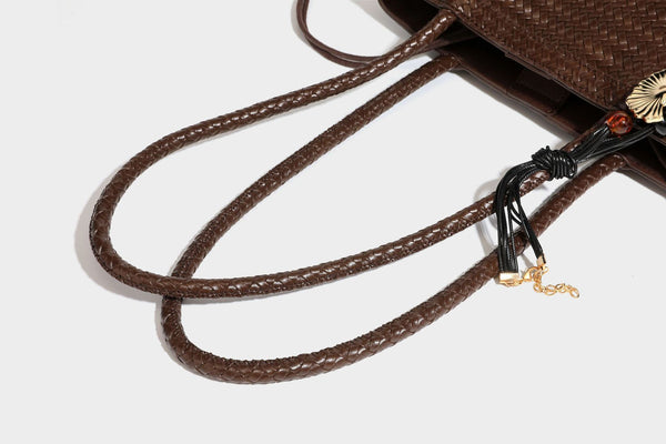 Structured woven leather-look tote bag in dark brown with long shoulder straps, side drawstring ties, and gold filigree