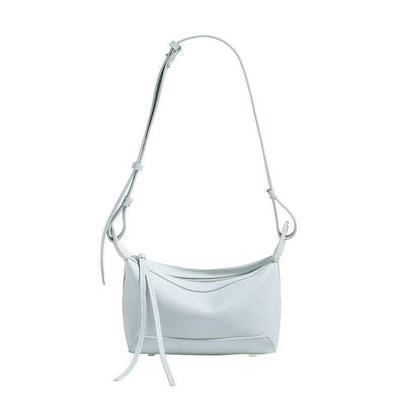 Small structured mini crossbody shoulder bag with pebbled texture, knotted adjustable strap, top zip closure, and gold-tone