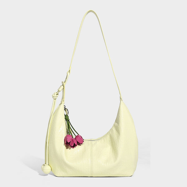 Slouchy crescent half-moon shoulder bag in pink pebbled textured finish with floral charm and knotted side detail, detail