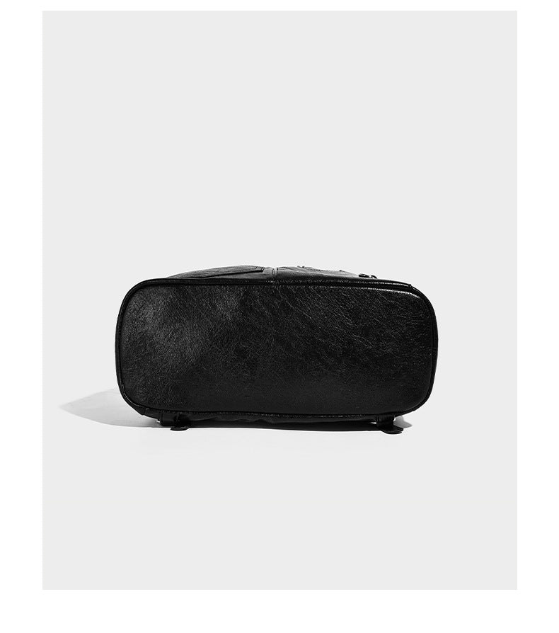 Glossy black convertible bucket backpack with silver grommet-studded straps, drawstring cinch closure, and front zip pocket
