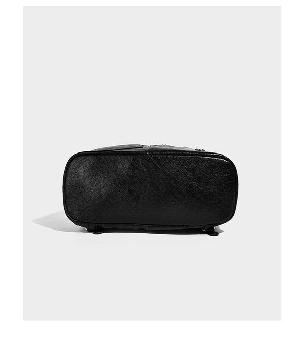 Glossy black convertible bucket backpack with silver grommet-studded straps, drawstring cinch closure, and front zip pocket