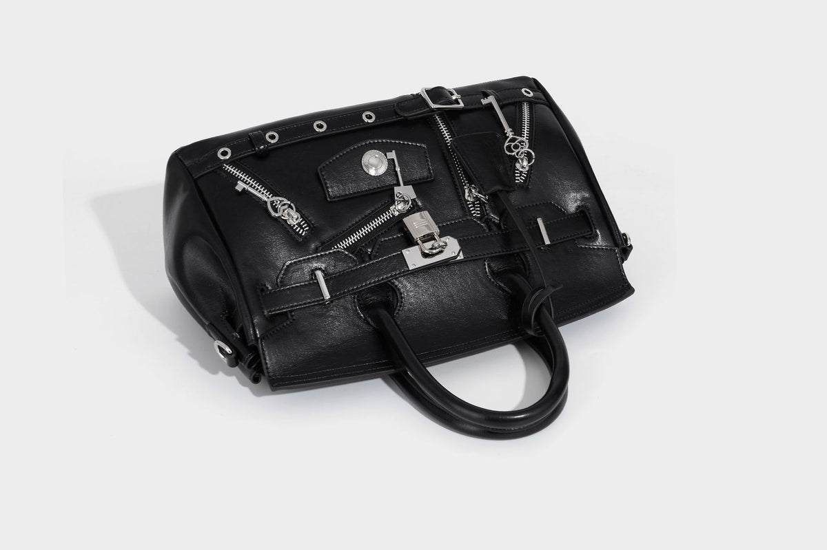 Structured black leather-look satchel bag with silver padlock hardware, front zip pockets, key charms, and top handles