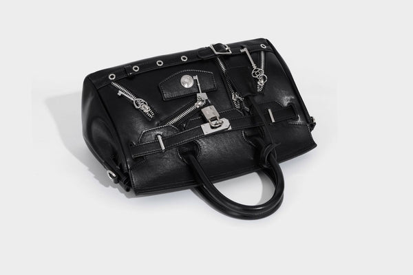Structured black leather-look satchel bag with silver padlock hardware, front zip pockets, key charms, and top handles