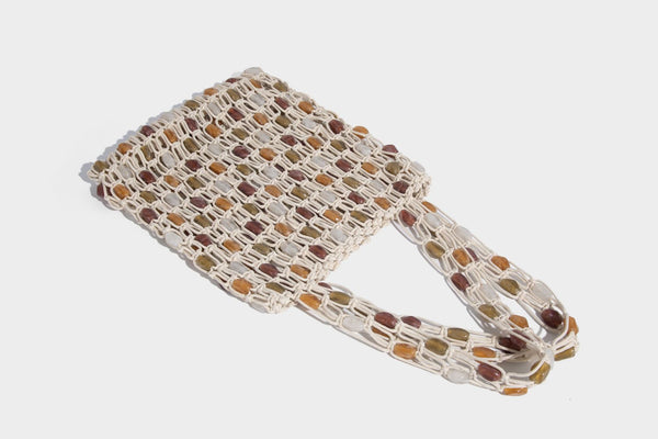 Cream macramé open-weave tote bag with multicolor amber olive and translucent bead accents and woven shoulder straps, detail